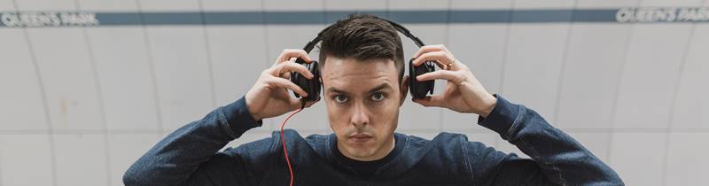 man holding headphones with a stare